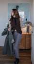 Woman holding a green coat in a room with a painting on the wall.