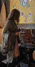Woman in a green coat standing in a restaurant with a colorful painting on the wall.