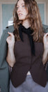 Woman wearing a brown top and olive green coat indoors