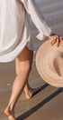 Person holding a straw hat on a beach