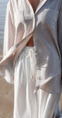Person wearing a light-colored shirt and white pants with a blurred background