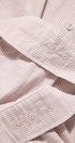 Close-up of a light pink corduroy shirt with embroidered text on the collar and sleeve.