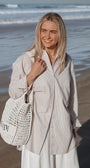 Woman holding a woven bag on a beach