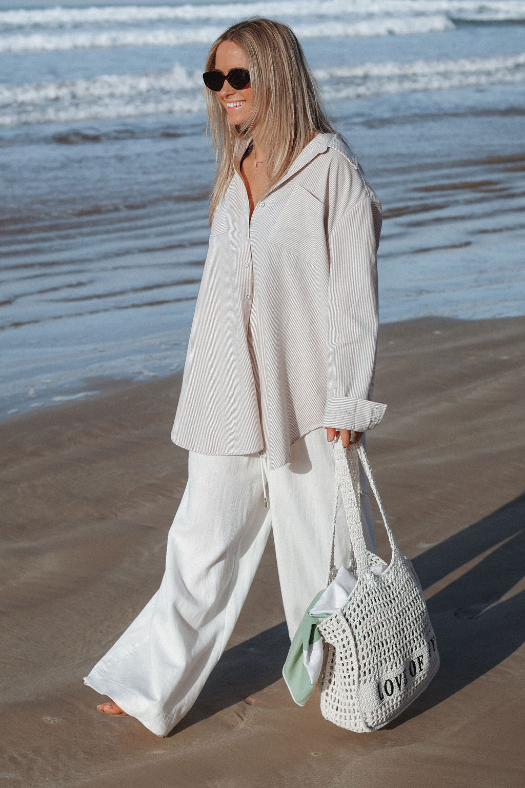 Woman in light clothing holding a white bag on a beach