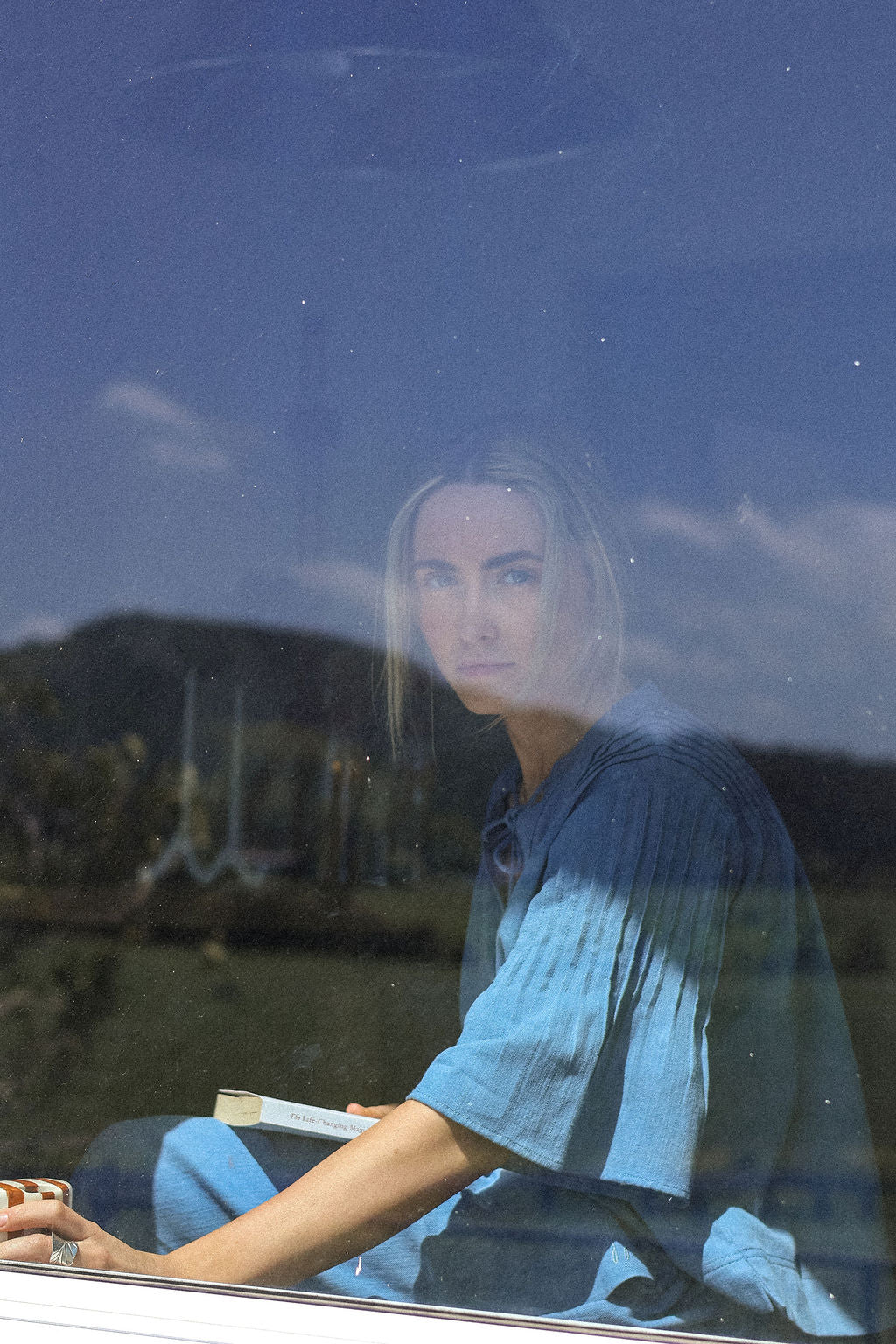 Person sitting inside a vehicle with a scenic reflection on the window