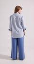 Person wearing a light blue shirt and wide-leg pants on a white background