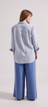 Person wearing a light blue shirt and wide-leg pants on a white background
