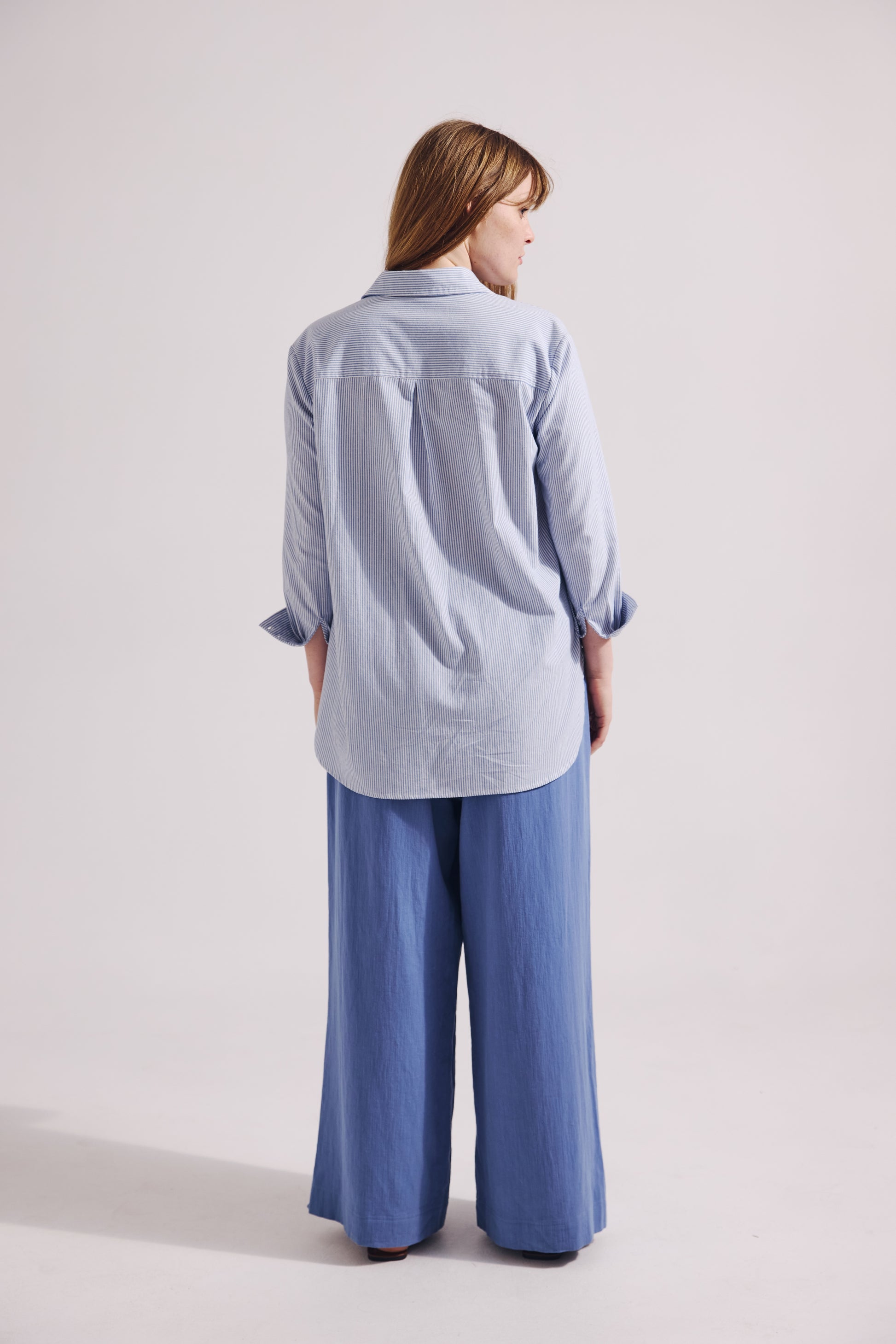 Person wearing a light blue shirt and wide-leg pants on a white background
