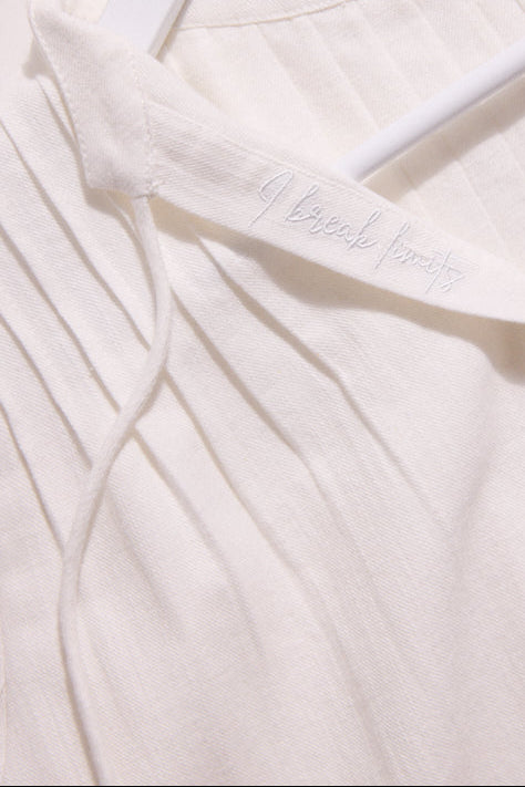 Close-up of a white garment with 'Ibreath' embroidery on a light background