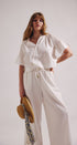 Woman wearing a white outfit with a plain background