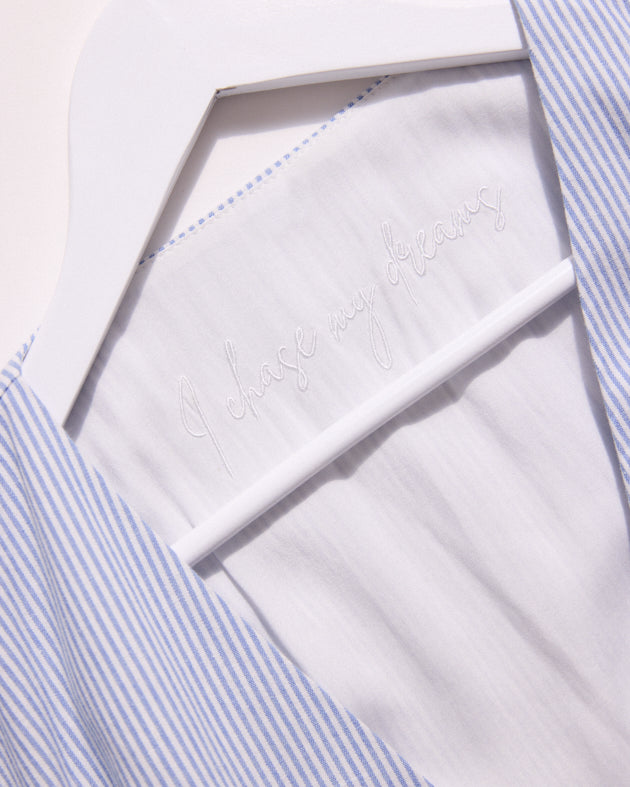 Close-up of a white shirt with blue striped collar and cuffs.