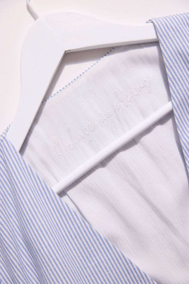 Close-up of a white shirt with blue striped collar and cuffs.