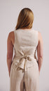 Woman wearing a beige sleeveless top and pants set against a plain background