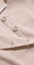 Close-up of a beige fabric with buttons and embroidered text on a light background
