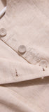 Close-up of a beige fabric with buttons and embroidered text on a light background