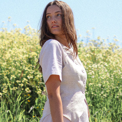 Woman in a white dress standing in a field with a clear blue sky.