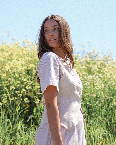 Woman in a white dress standing in a field with a clear blue sky.