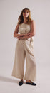 Woman wearing a beige sleeveless jumpsuit on a plain background