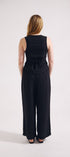 Person wearing a black sleeveless jumpsuit on a white background