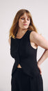 Woman wearing a black sleeveless top and skirt against a white background