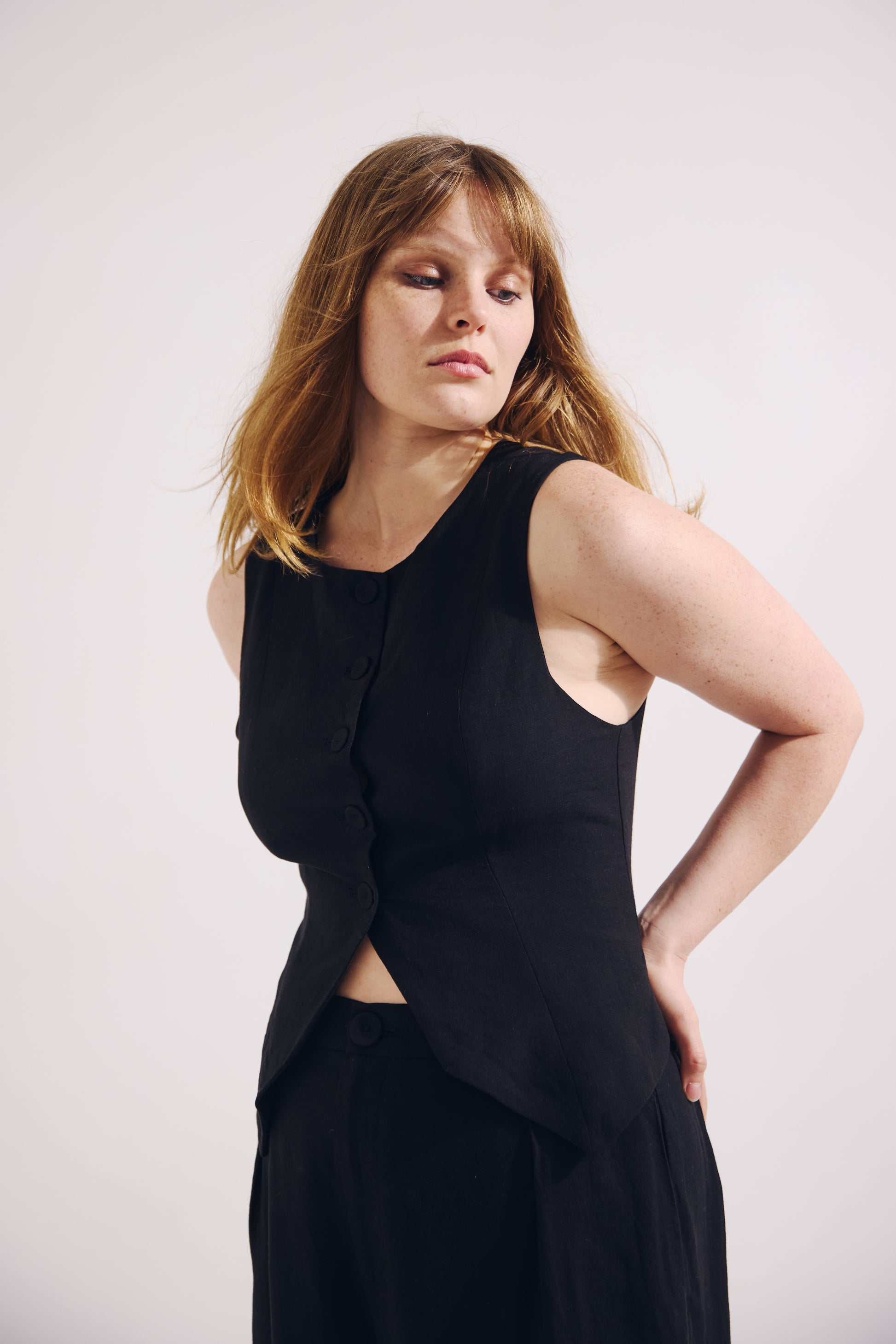 Woman wearing a black sleeveless top and skirt against a white background