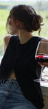 Person sitting by a window holding a glass of red wine