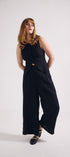 Woman wearing a black sleeveless top and wide-leg pants on a white background