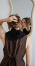 Person adjusting hair in front of a mirror with a neutral background