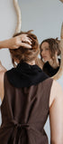 Person adjusting hair in front of a mirror with a neutral background