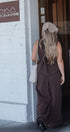 Person in a brown dress standing outside a building with a sign that reads 'Old Grain Store'.