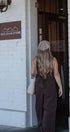 Woman entering a building with 'Gold Grain Store' sign on a white brick wall.