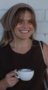 Woman holding a white mug with a brown background