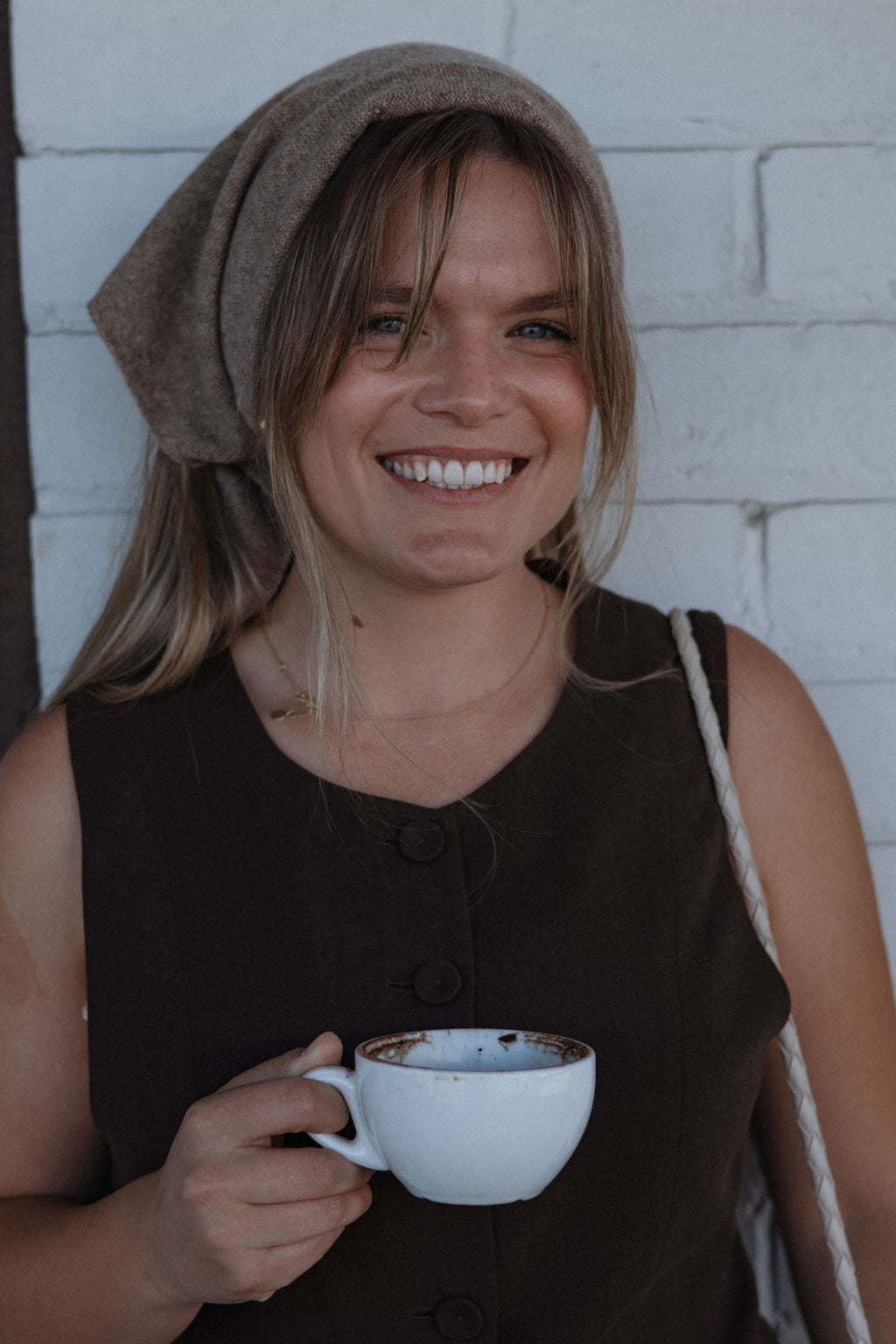 Woman holding a white mug with a brown background