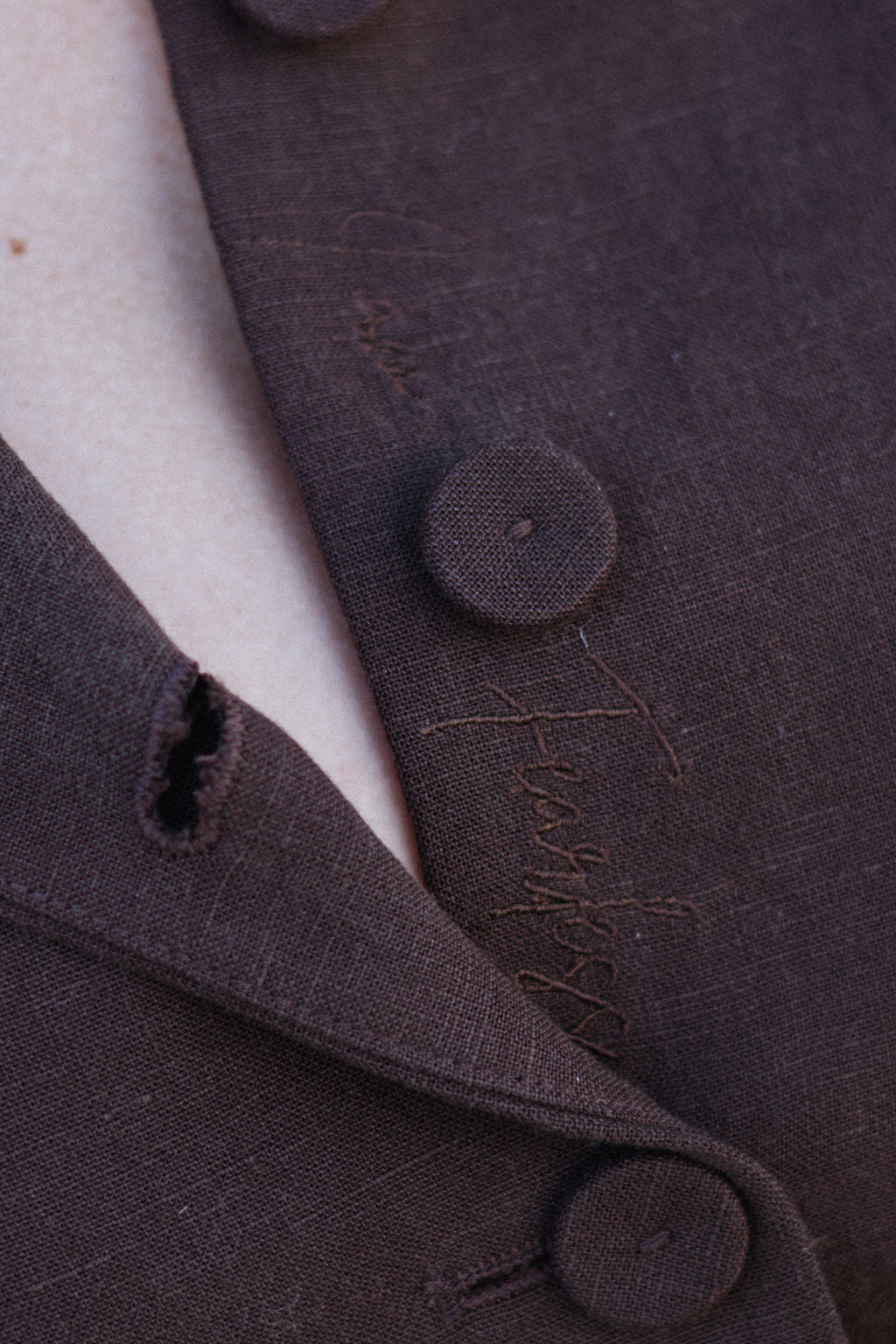 Close-up of a brown textured fabric with buttons and stitching details.