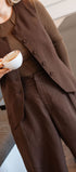 Person wearing a brown outfit holding a cup, standing indoors.