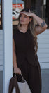 Woman in a brown dress standing outdoors with a blurred background
