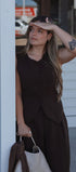 Woman in a brown dress standing outdoors with a blurred background