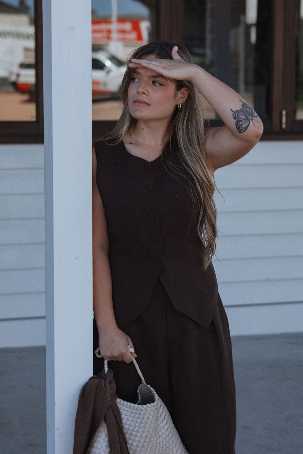 Woman in a brown dress standing outdoors with a blurred background
