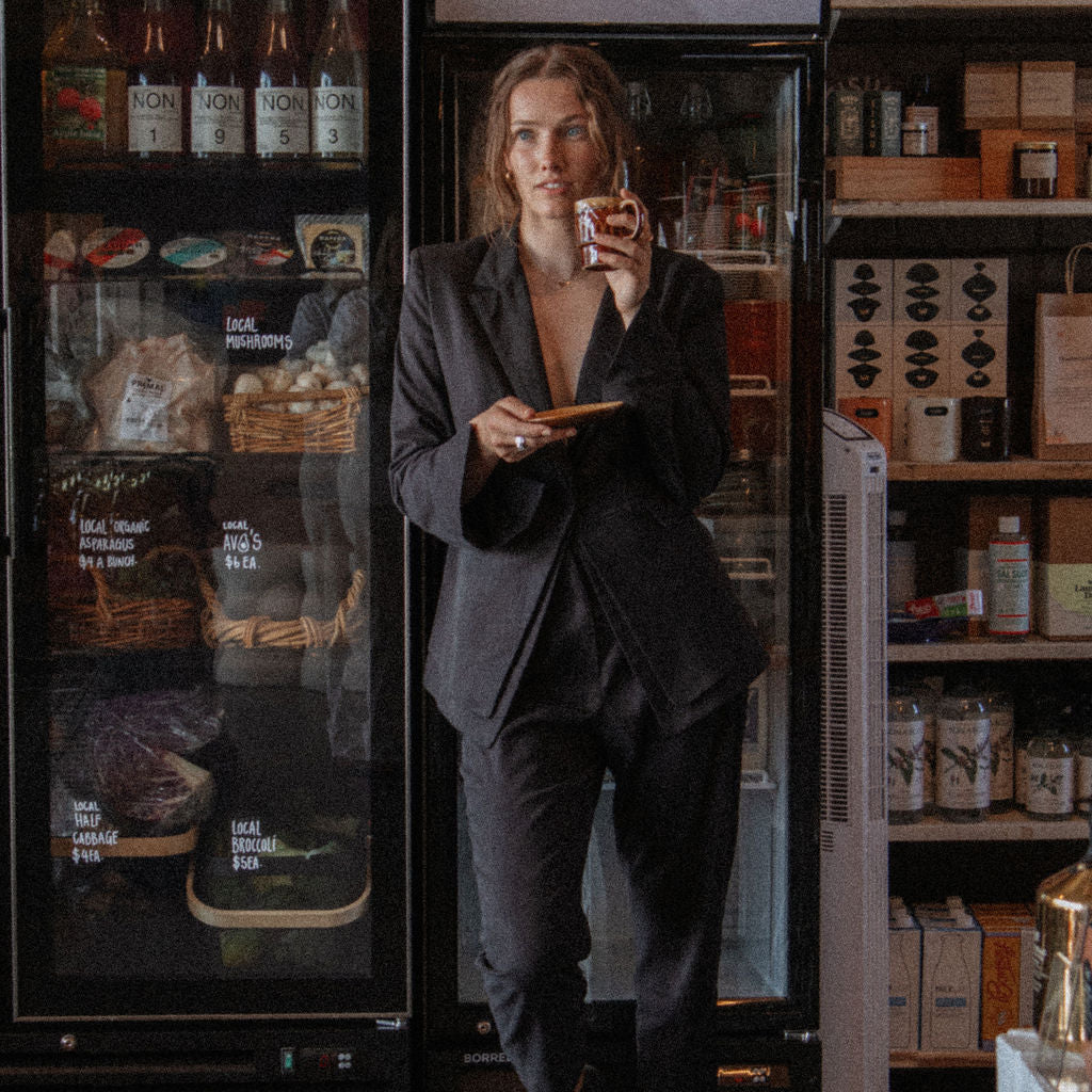 Person in a dark suit standing in front of a refrigerator in a store.