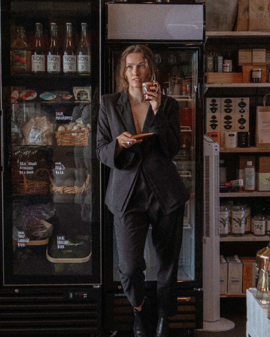 Person in a dark suit standing in front of a refrigerator in a store.
