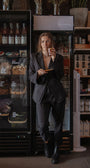 Person in a dark suit standing in front of a refrigerator in a store.