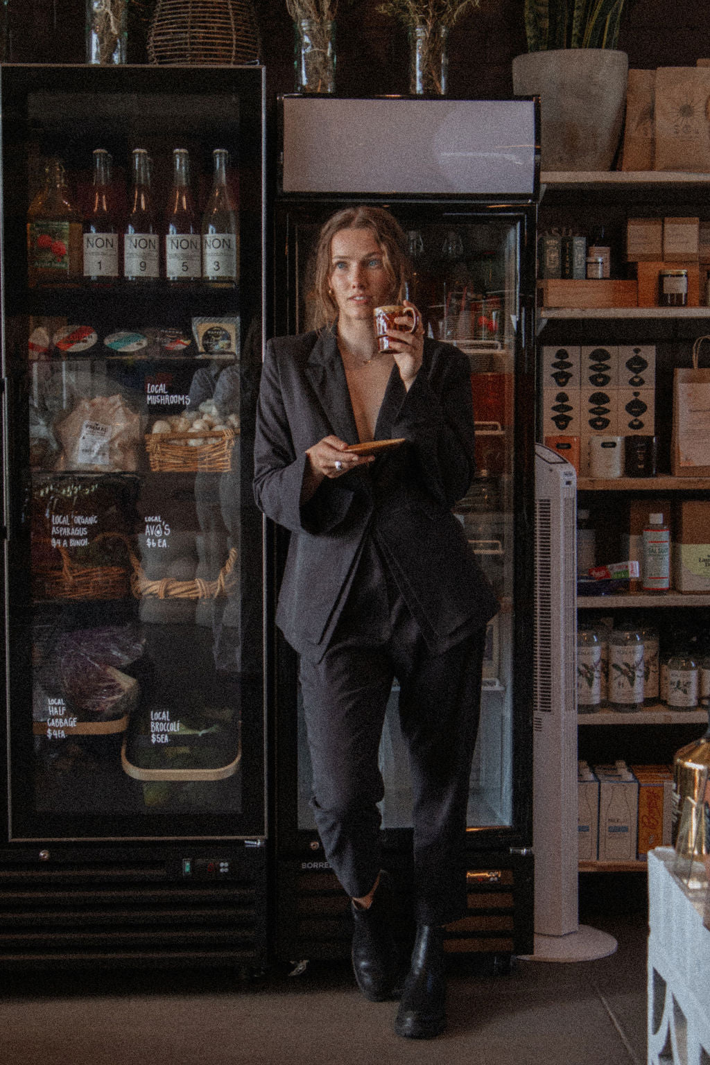 Person in a dark suit standing in front of a refrigerator in a store.
