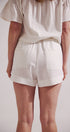 Person wearing a white top and shorts on a plain background