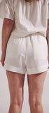 Person wearing a white top and shorts on a plain background
