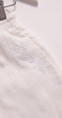 White garment with 'Justine' embroidered on it, hanging against a white background.