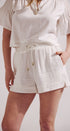 Person wearing a white outfit with shorts and a top on a plain background