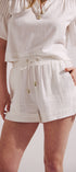 Person wearing a white outfit with shorts and a top on a plain background