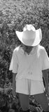 Person wearing a white cowboy hat and outfit standing in a field of tall grass.
