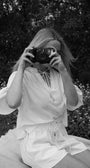 Person taking a photo with an old camera in a natural setting