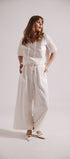 Woman wearing a white outfit with wide-leg pants on a plain background